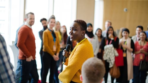 Smiling female speaker with microphone on stage, blogpost about leadership championing innovation.